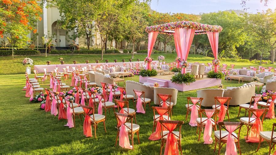 An elegant setting of chairs facing towards the stage in a lawn on a sunny day at Essentia Luxury Resort & Spa, Udaipur. 