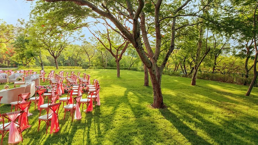 An elegant setting of chairs facing towards the stage in a lawn on a sunny day at Essentia Luxury Resort & Spa, Udaipur. 