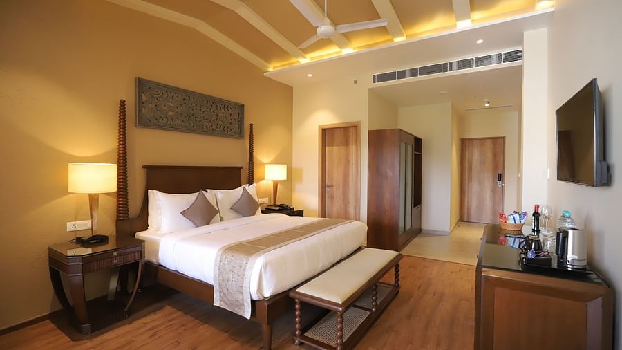 Deluxe room with a king size bed placed in front of a TV at Essentia Luxury Resort & Spa, Udaipur.