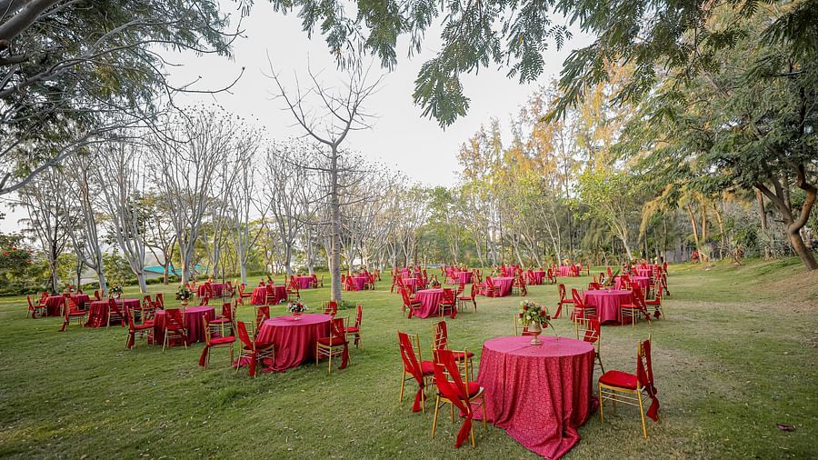 Red-coloured chairs and tables placed in the lawn at Essentia Luxury Resort & Spa, Udaipur.