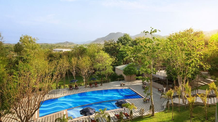 Aerial view of a swimming pool surrounded by trees at Essentia Luxury Resort & Spa, Udaipur.