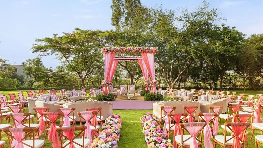 An elegant setting of chairs facing towards the stage in a lawn on a sunny day at Essentia Luxury Resort & Spa, Udaipur. 