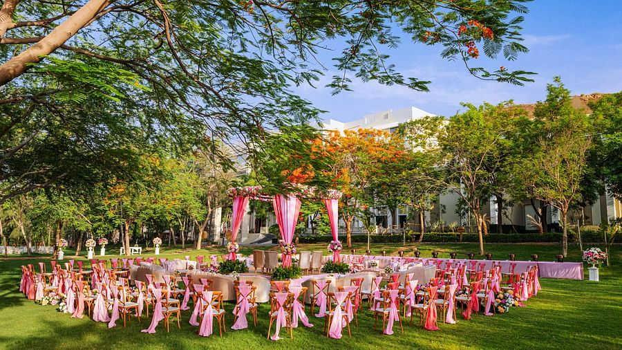 An elegant setting of chairs facing towards the stage in a lawn on a sunny day at Essentia Luxury Resort & Spa, Udaipur. 