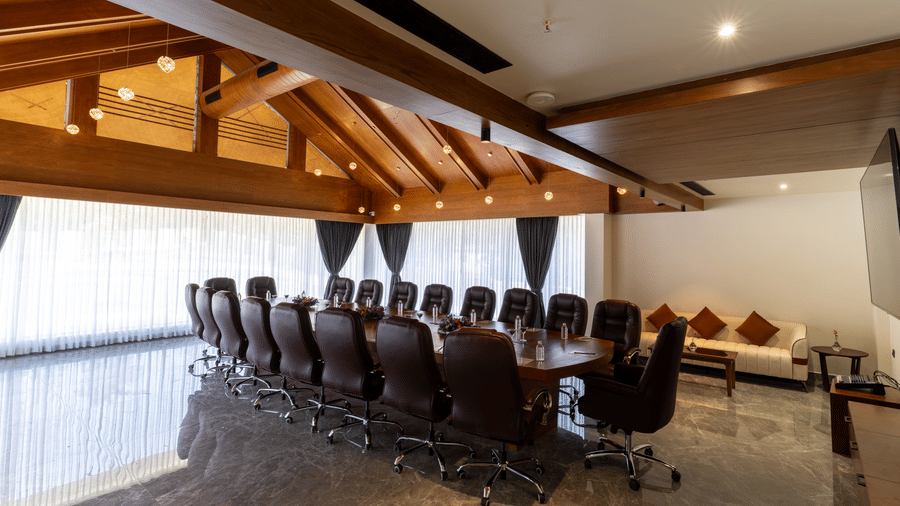 Board room with a long wooden table, leather chairs, and a wooden ceiling with recessed lighting at Essentia Resort & Spa, Sirsi 
