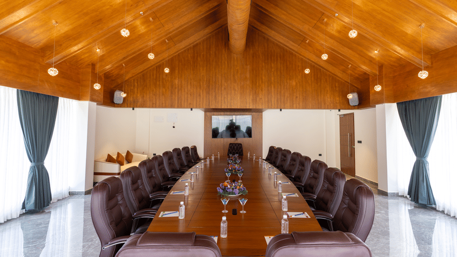 Board room with a long wooden table, leather chairs, and a wooden ceiling with recessed lighting at Essentia Resort & Spa, Sirsi 