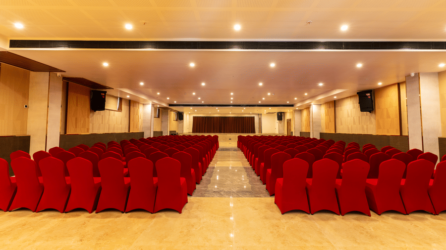  banquet hall set up, featuring rows of velvet chairs and a stage at the front at Essentia Resort & Spa, Sirsi 