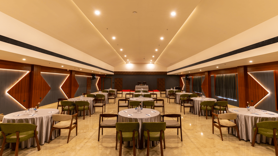 banquet hall with multiple round tables set for a meal at Essentia Resort & Spa, Sirsi 