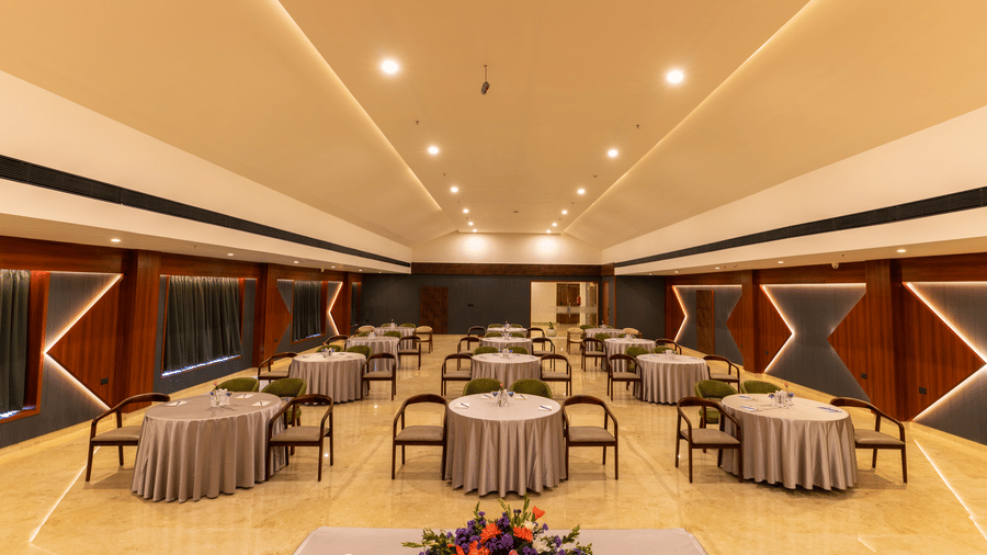 banquet hall with multiple round tables set for a meal at Essentia Resort & Spa, Sirsi 