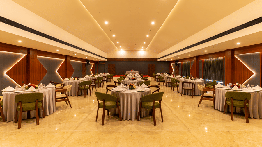 banquet hall with multiple round tables set for a meal at Essentia Resort & Spa, Sirsi 