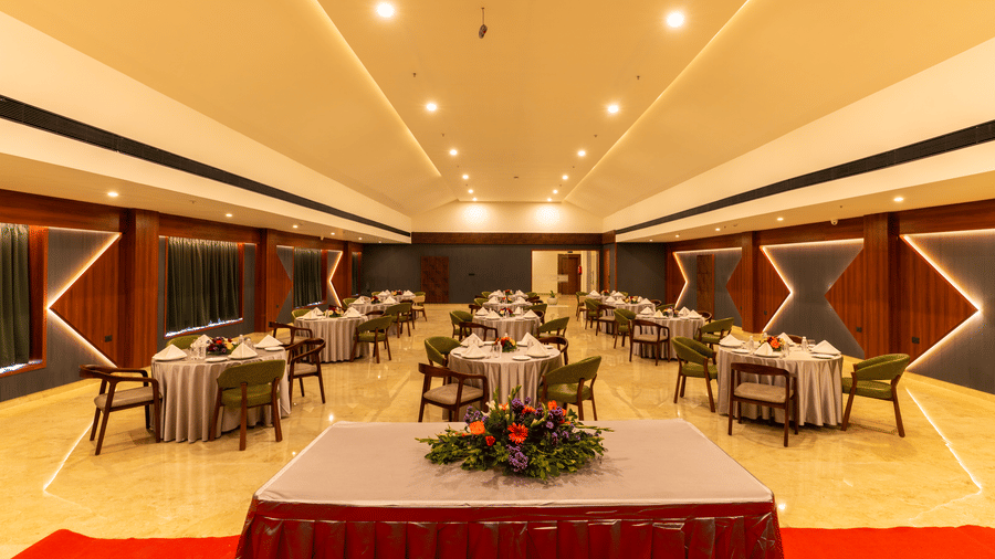 banquet hall with multiple round tables set for a meal at Essentia Resort & Spa, Sirsi 