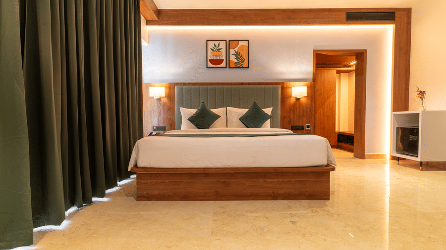 bedroom with a large bed, two pillows, two lamps, and artwork on the wall at Essentia Resort & Spa, Sirsi  