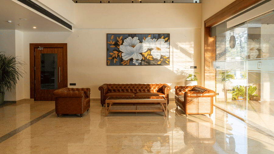 indoor lobby area with wooden furniture and a large painting at Essentia Resort & Spa, Sirsi 