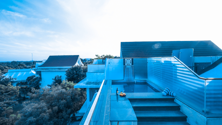 Elevated rooftop view at Estherea Resort & Spa, Jaipur showing a private pool with steps, overlooking trees and lower resort buildings.