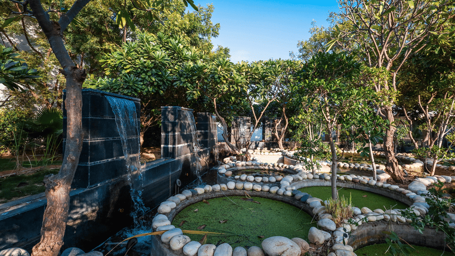 A daytime view of the modern stone water walls and circular ponds in the landscaped gardens of Estherea Resort & Spa, Jaipur.