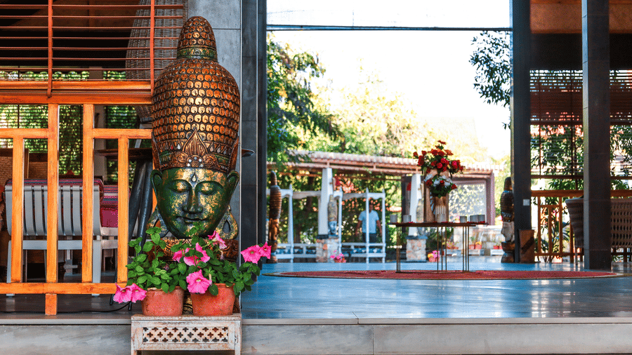 Decorative Buddha head sculpture on a pedestal at Estherea Resort & Spa, Jaipur, situated in a semi-open lounge area with wooden accents.