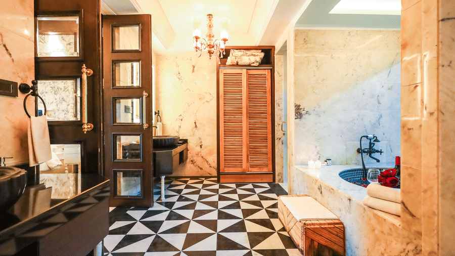 Bathroom at Estherea Resort & Spa, Jaipur, with black and white checkered floor tiles, a built-in bathtub, and a wooden wardrobe.