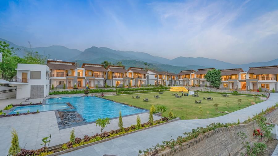A wide angle shot of the resort during a bright day featuring law, swimming pool and villas.