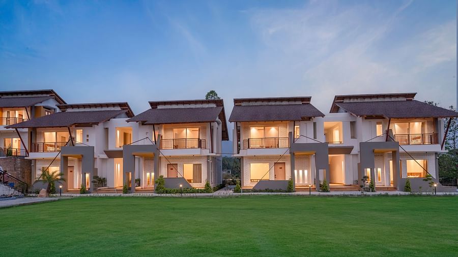 A row of luxurious villas with lit windows, surrounded by a green lawn.