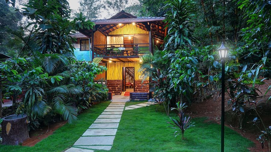 A facade image of the Group Wooden Cottage covered in lush green trees - Evergreen County