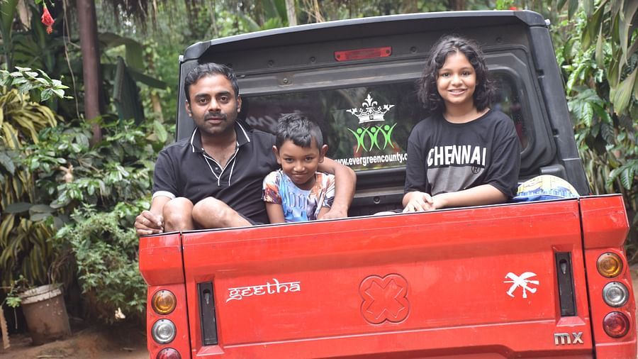 A family of three on the back of a red truck looking at the camera - Evergreen County