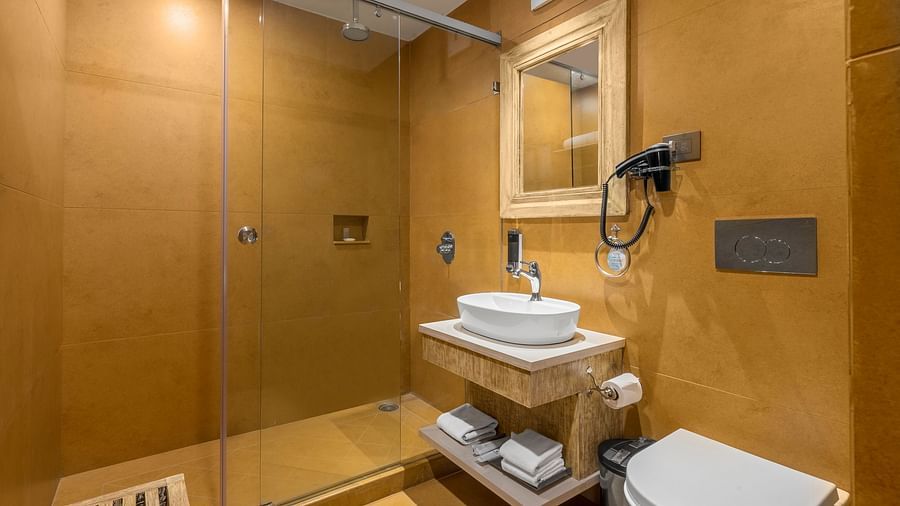 Attached bathroom at Fishermen's Lodge, Bhimtal, featuring wooden furnishings and a stylish wall-hanging mirror for a cosy atmosphere.