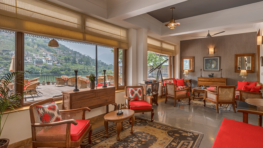 A cozy lounge area featuring comfortable sofas, chairs, and elegant antique interiors, offering stunning views of the lake and mountains from inside Fishermen's Lodge.