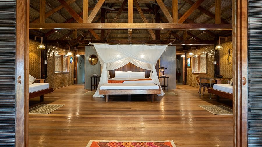 Interior of a room at Flower Island Resort with a canopy bed, wooden ceiling, and side lamps.