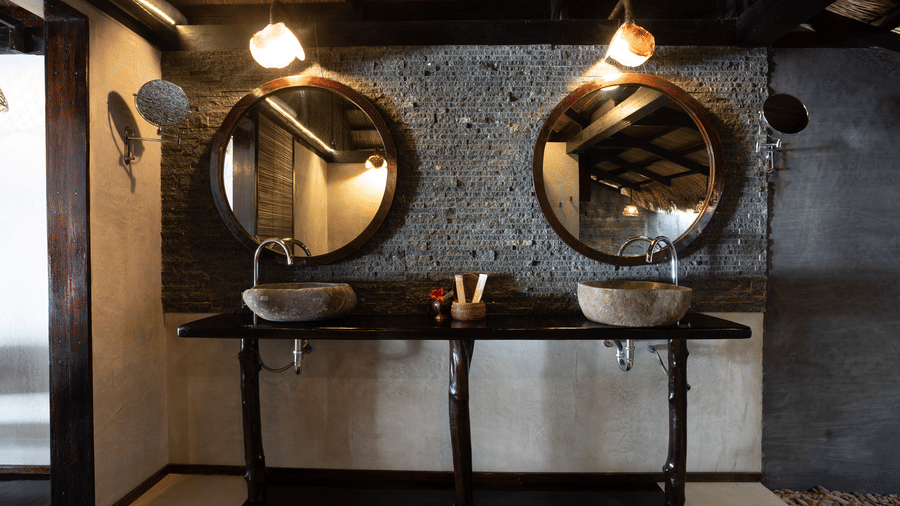 A bathroom with mirrors, two stone sinks, and lights at Flower Island Resort.