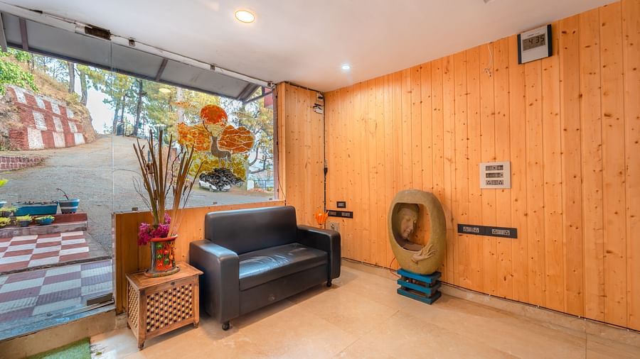 Sitting area at the reception of Flutter Hotels and Resorts, Lansdowne with a sofa, wooden decors and flower vase.