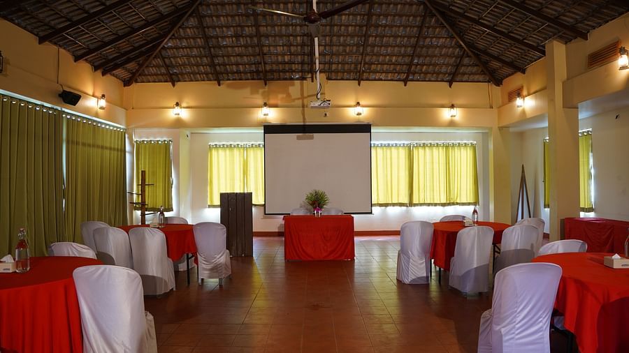 Another view of the event hall at Forest Escapes Koyna, showing tables with red and white accents.