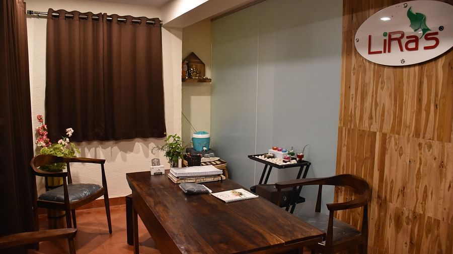 This image shows a welcoming spa reception area at Forest Escape, featuring a wooden desk, chairs, and a sign with green lettering.