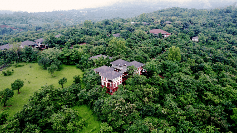 Aerial view of Forest Escapes in Koynanagar featuring its buildings surrounded by dense greenery under a misty sky