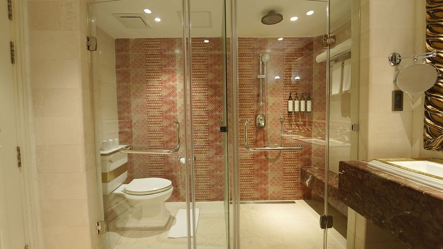 A bathroom at Fragrant Nature Cochin featuring a glass-enclosed shower and toilet with patterned red tiles and modern fittings.
