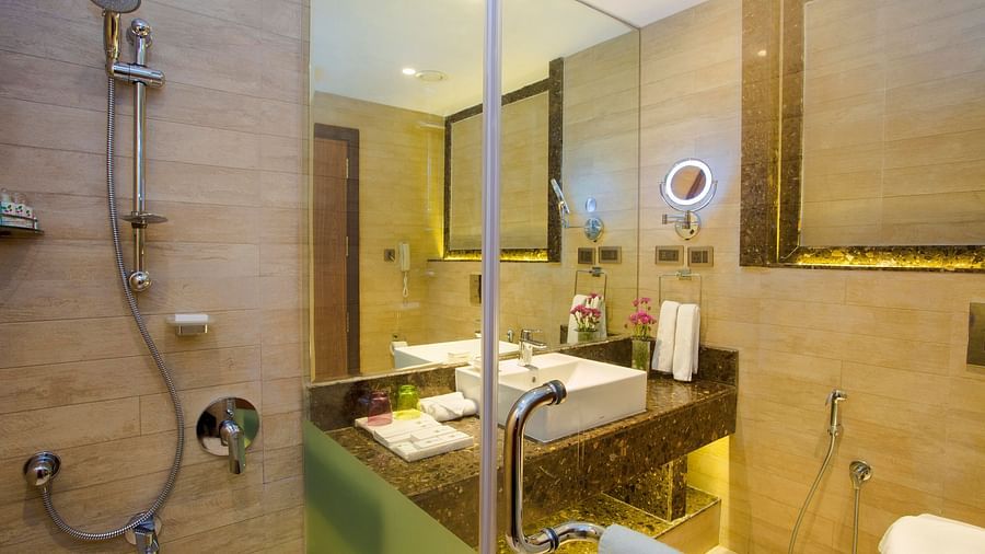Bathroom with a mirror above the washbasin, separate lighting for it, and a glass partition separating the shower area.