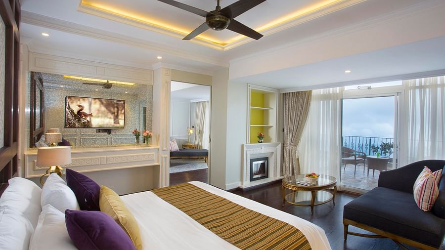 Wild Orchid Suite with Private Terrace and Mountain View with furniture arranged before the bed and a balcony view visible directly from the bed
