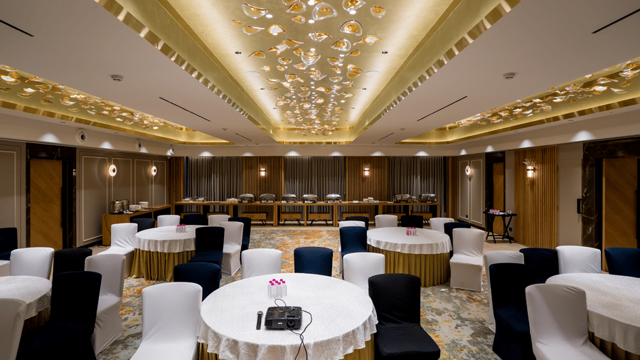 Galaxy 1 banquet hall at Gemini Continental featuring a decorated ceiling, a carpeted floor, and multiple round tables with chairs.