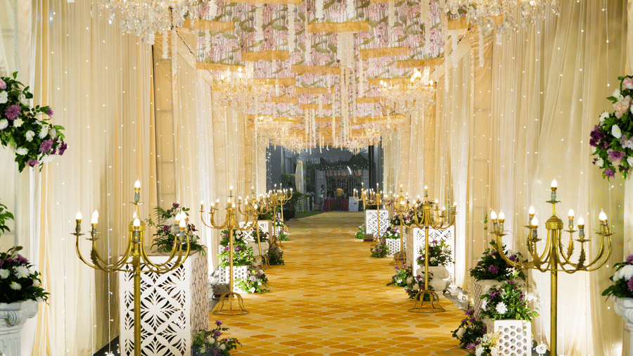 Lawn walkway at Gemini Continental featuring a patterned carpet, golden candelabras, and elegant chandeliers under floral drapes.