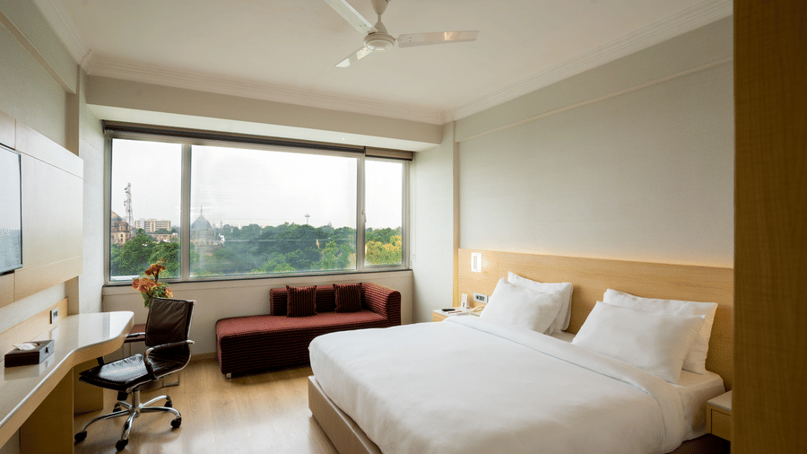 A Luxury Room at Gemini Continental with a bed, a sofa, a desk with a chair, and a ceiling fan.