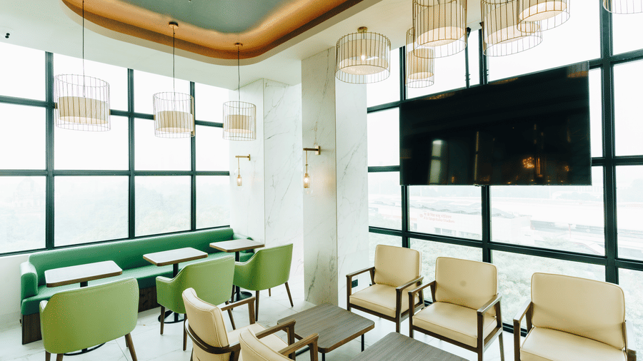 A bright and stylish lounge area with modern seating and large windows, reflecting the welcoming ambience of Gemini Continetal, a hotel near Lucknow City Railway Station.
