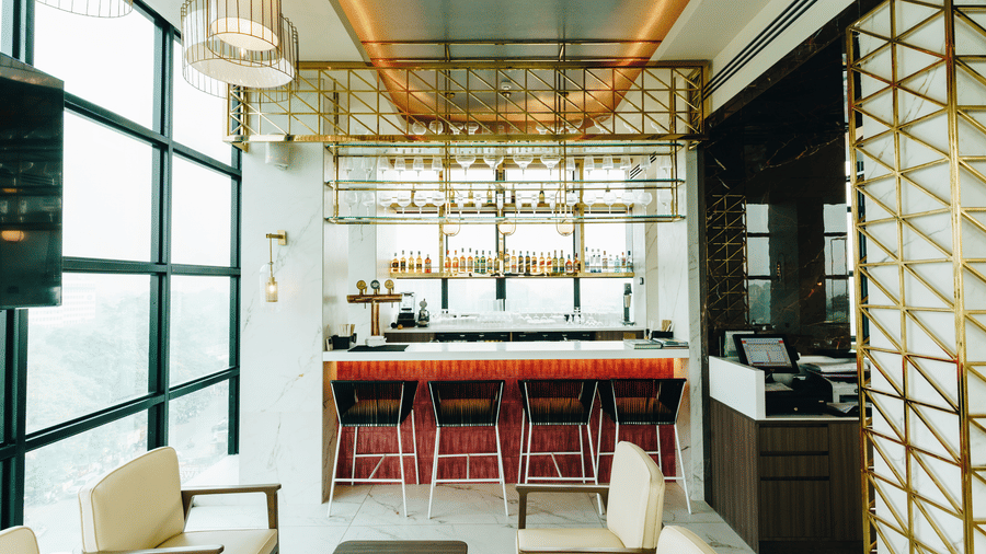 Sleek interior of Seven Heaven Bar at Gemini Continental with seating arrangements and a bar lined with stools, bottles and wine glasses.