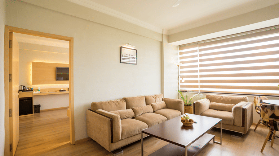 Spacious living area of a Suite at Gemini Continental with 2 sofas, coffee table, and a smaller table. An open door reveals a second room with a television and desk.