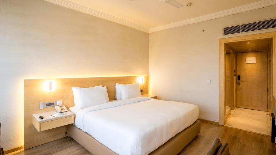 A Superior Room at Gemini Continental with a bed in the centre, matching nightstands, an A/C unit, and an attached bathroom. 