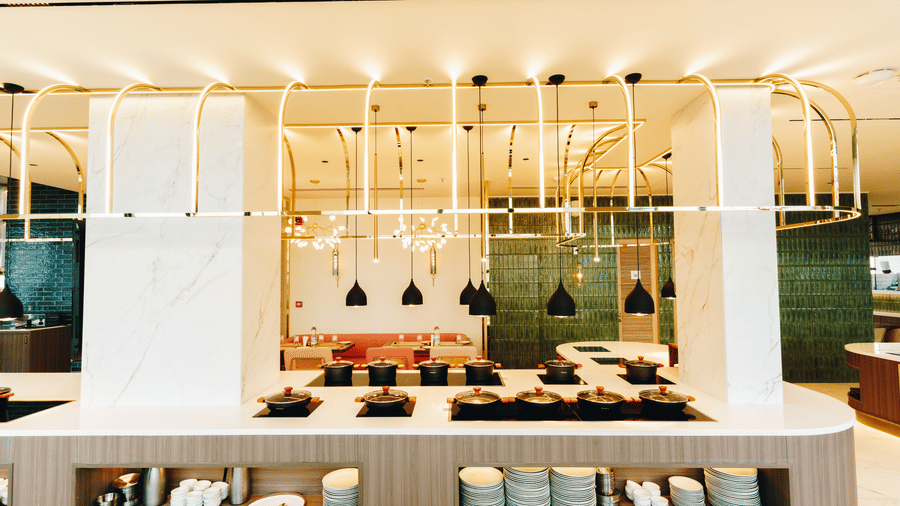 A modern, well-lit buffet counter in Zaika restaurant featuring gold accents and black pendant lights - Gemini Continental
