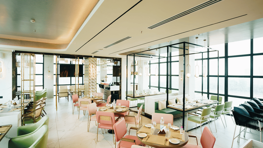 Interior of Zaika restaurant at Gemini Continental with pastel chairs, marble floors, large windows, and neatly set tables in a stylish, airy dining space.