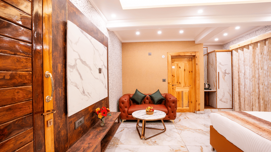 A room view showing a red leather sofa and marble-top coffee table against a wood-panelled wall - Golden Oak By The Lake Hill, Khurpatal