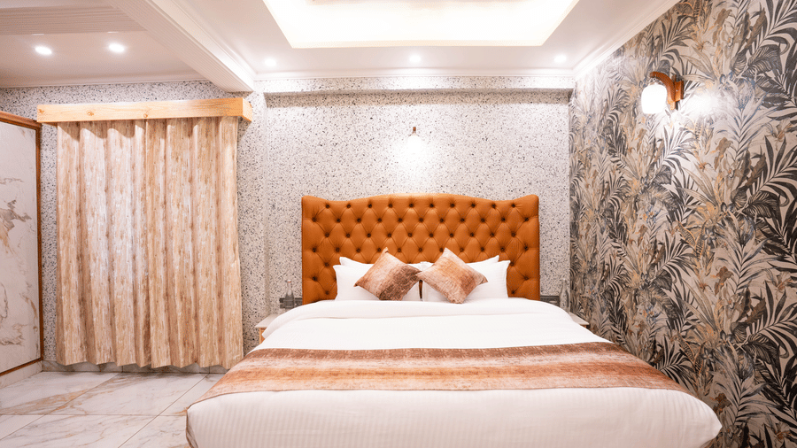 An elegant suite bed with a decorative headboard set against textured grey and leaf-patterned walls - Golden Oak By The Lake Hill, Khurpatal