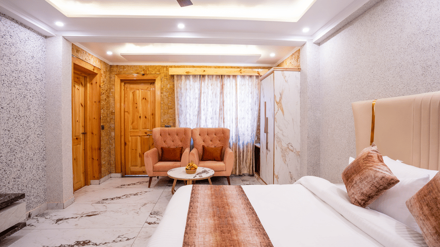 A bright, spacious hotel suite featuring marble flooring, a plush bed, and wooden doors - Golden Oak By The Lake Hill, Khurpatal