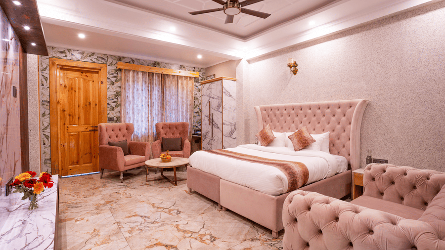 A luxury suite view showing a pink velvet seating area and a large bed with premium linens - Golden Oak By The Lake Hill, Khurpatal