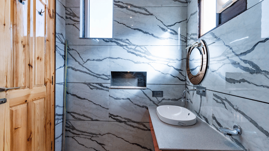 A modern bathroom featuring grey marble-patterned wall tiles and a wooden door - Golden Oak By The Lake Hill, Khurpatal