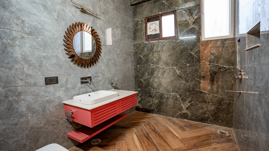 A sleek bathroom with dark grey stone walls, a floating red vanity, and a circular mirror - Golden Oak By The Lake Hill, Khurpatal